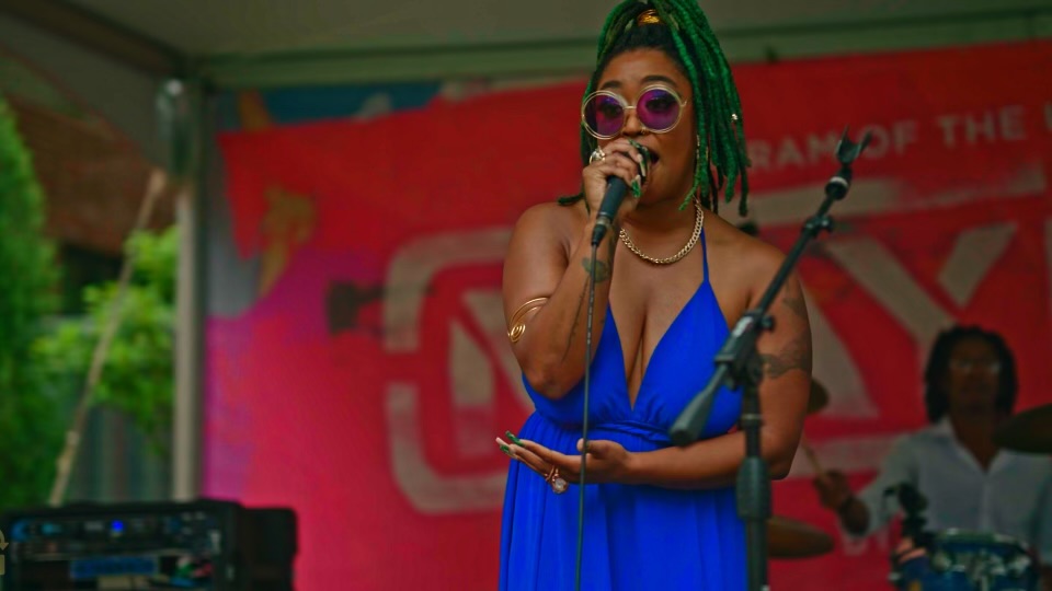Emani singing at an outdoor festival stage with her live band