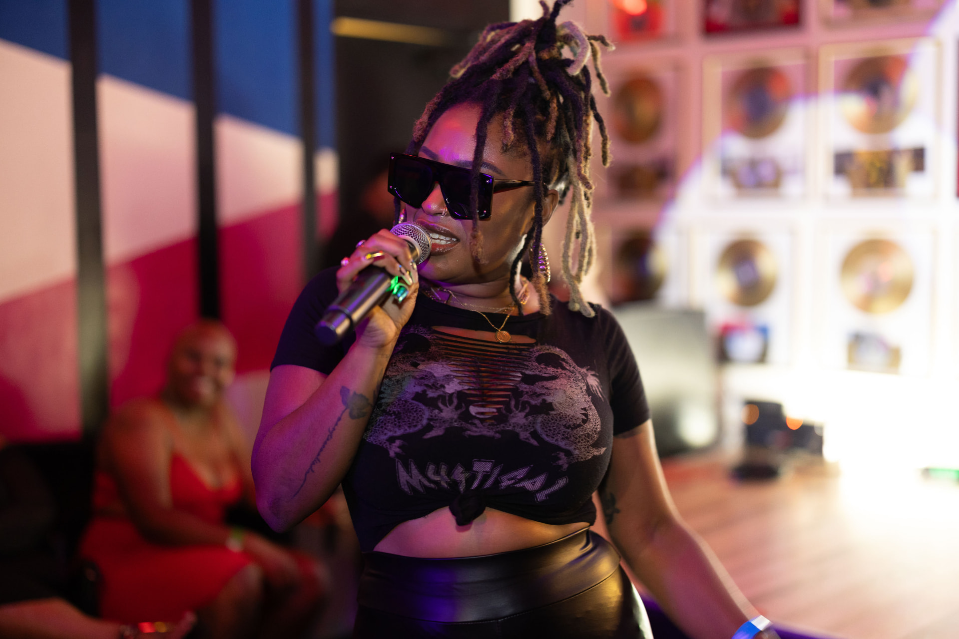 Emani performing on the mic in a warmly lit venue